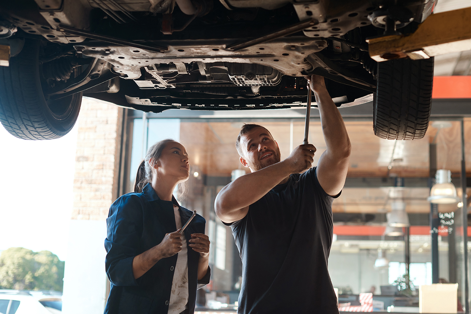 Well do a better job in half the time. Shot of two mechanics working together under a lifted car